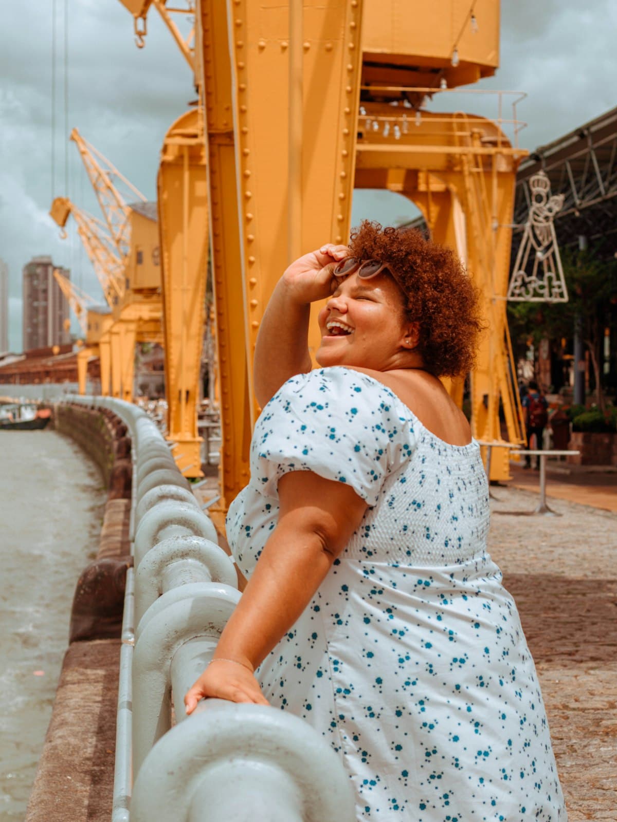 A woman in a floral dress laughing outdoors