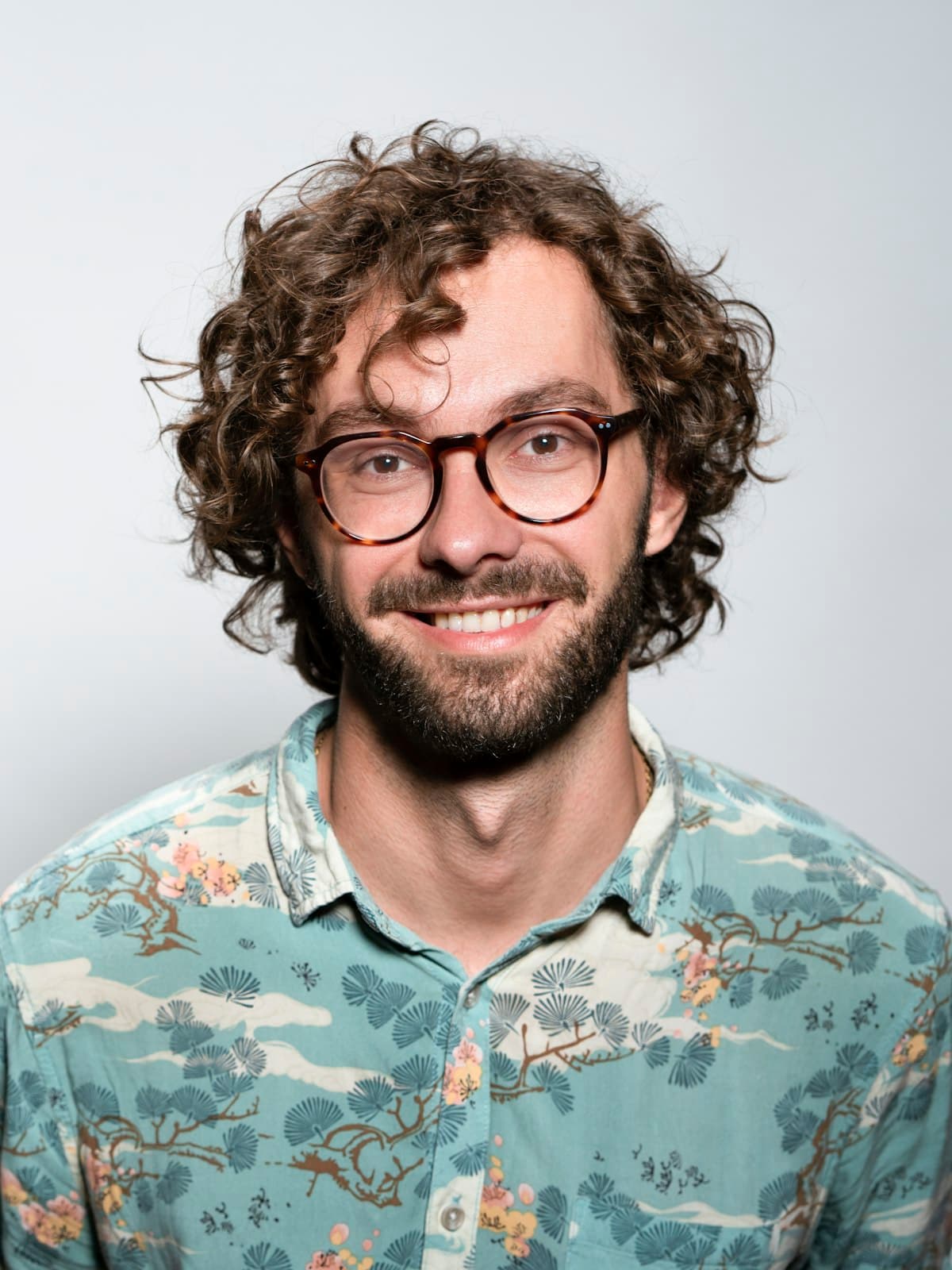 A man with glasses and a beard smiling
