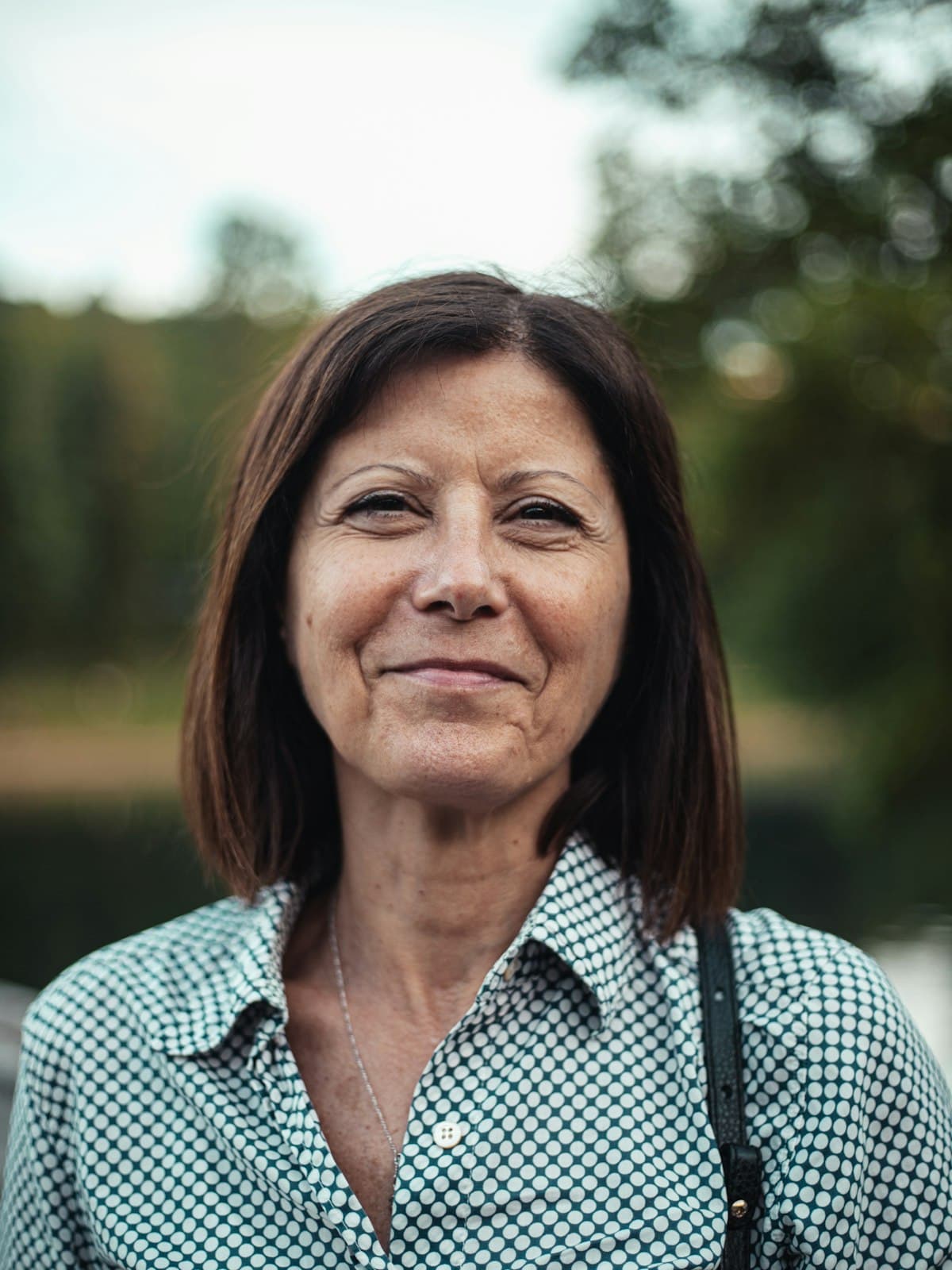 A woman in a checked shirt smiling outdoors