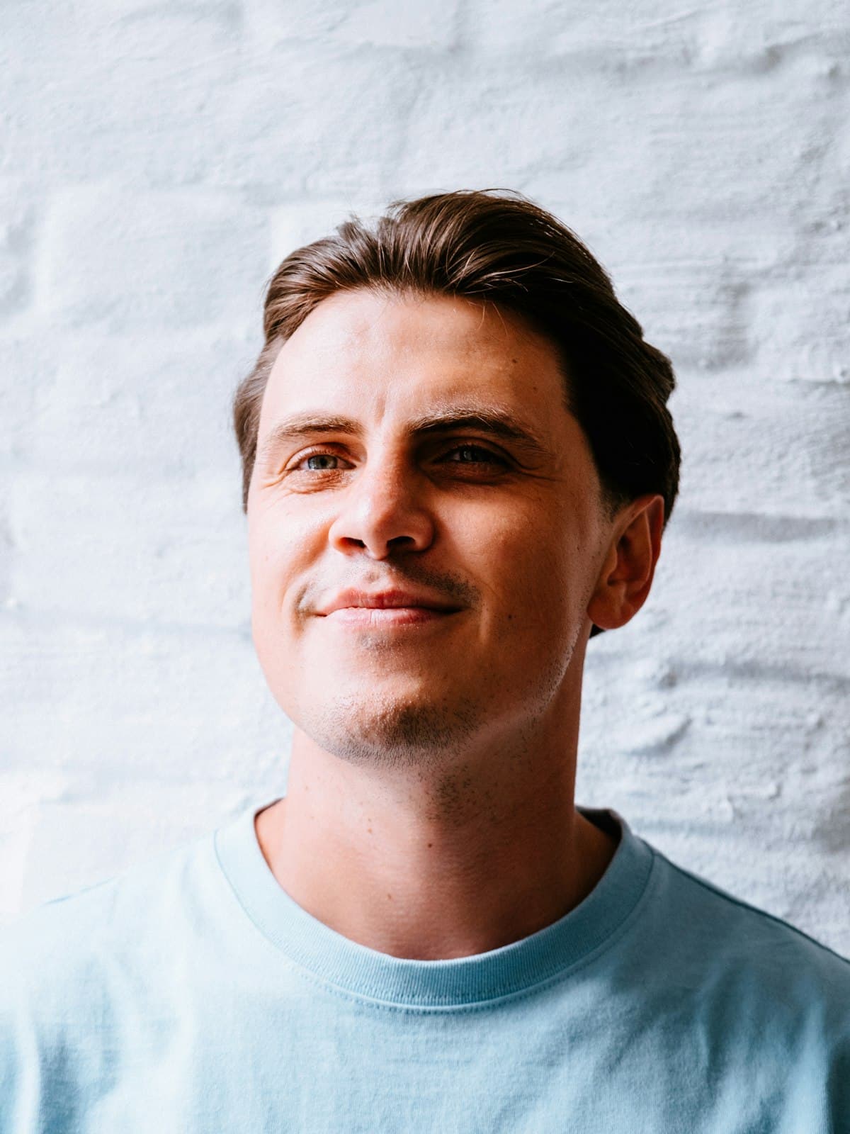 A man in a light blue t-shirt smiling